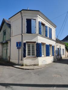an old white building with blue shutters on a street at Lumières de Tuffeau in Château-du-Loir