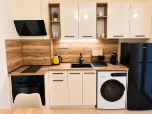 a kitchen with white cabinets and a sink and a dishwasher at AM Sea Studios in Ravda