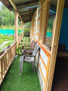 a porch with two chairs sitting on the grass at Pulga Inn in Kalgha +4 photos