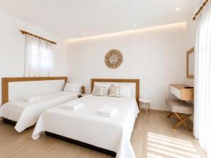 two beds in a bedroom with white walls and wooden floors at Cyclades Blue in Ornos