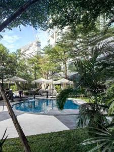 a swimming pool in a park with trees and a building at 千禧大厦 in Pattaya South