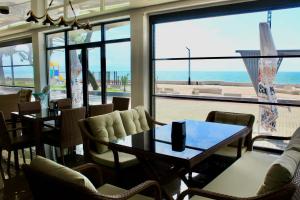 a restaurant with a table and chairs and a view of the ocean at Hotel Zich in Kobuleti