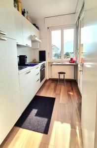 a kitchen with white cabinets and a wooden floor at Wohnung nr 103 in Muralto