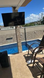 a television sitting on a patio with a chair and a pool at Casa com piscima e área goutmet in Camaçari