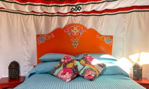 a bed with an orange headboard and pillows on it at La Dorépontaise YOURTE MONGOLE in Pondaurat