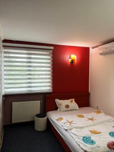 a bedroom with a red wall with a bed and a window at Harmony Rooms & Apartments in Vogošća
