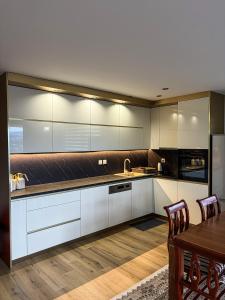 a kitchen with white cabinets and a wooden table at Harmony Rooms & Apartments in Vogošća