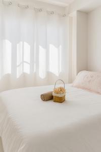 a white bed with a towel and a basket on it at Nice location in the persimmon condo in Cebu City +25 photos