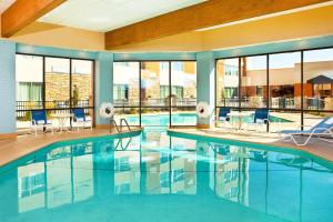 a pool in a hotel with chairs and tables and windows at Four Points By Sheraton - Saginaw in Saginaw