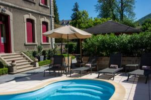 a swimming pool with chairs and an umbrella next to a house at La Villa de Mazamet in Mazamet