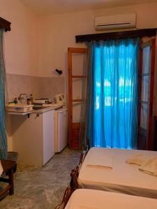 a room with a bed and a kitchen with a blue curtain at Studios Julia in Petra