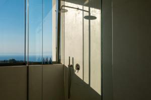 a bathroom with a glass door with a window at CAPO LEFKADA Villa 97 - Sea View - Two Private Pools in Tsoukalades