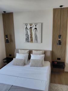 a bedroom with a white bed with three dresses on the wall at Apartman Sandra in Varaždin