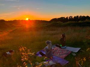 two girls sitting on a blanket in a field at sunset at Sunset view in Hereford