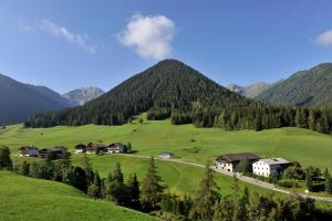 a village on a green hill with mountains in the background at B&B Monte in Kartitsch