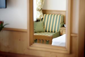 a mirror reflection of a green chair in a room at B&B Monte in Kartitsch