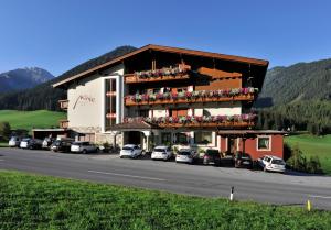 a large building with cars parked in front of it at B&B Monte in Kartitsch