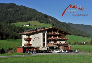 a building with cars parked in front of a mountain at B&B Monte in Kartitsch +2 photos