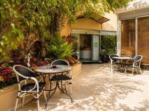 a patio with four chairs and tables in front of a store at Margosa Boutique Hotel Tel-Aviv Jaffa in Tel Aviv