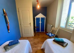 a room with two beds and a blue wall at La Dorépontaise CHAMBRE D'HOTES in Pondaurat