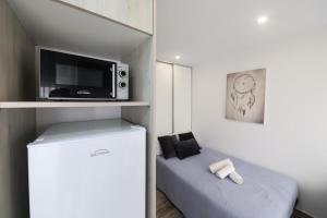 a small room with a bed and a microwave at Apartamentos e quartos Primorosa in Nazaré