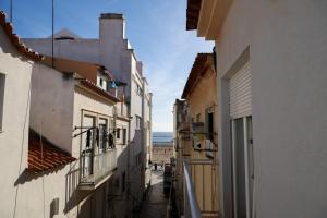 an alley between buildings with a view of the ocean at Apartamentos e quartos Primorosa in Nazaré