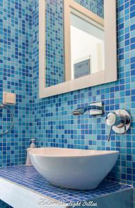 a blue tiled bathroom with a sink and a mirror at Kalami Sunlight Villa in Kalami