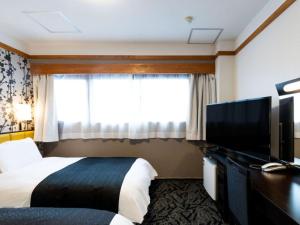 a hotel room with a bed and a flat screen tv at APA Hotel Karuizawa Ekimae Karuizawaso in Karuizawa