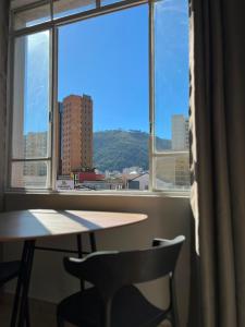 a table and a chair in front of a window at Studio no Centro com VISTA PARA O CRISTO in Poços de Caldas