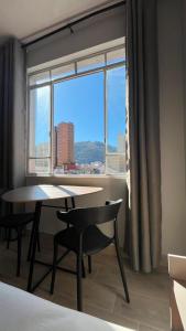 a table and chairs in a room with a large window at Studio no Centro com VISTA PARA O CRISTO in Poços de Caldas