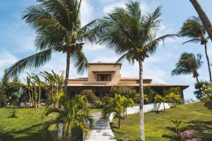 a house with palm trees in front of it at Pousada Villa Jodie in Fortim