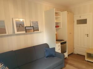 a living room with a blue couch and a kitchen at Dormare in Grzybowo