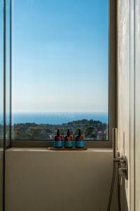 three bottles sitting on a window sill in a bathroom at CAPO LEFKADA Villa 71 - Sea View - Two Private Pools in Tsoukalades +48 photos