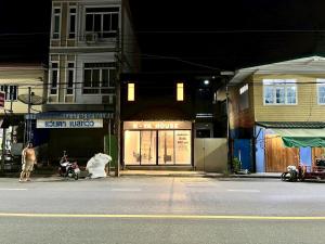 a woman is standing in front of a store on a street at K-YA house in Phitsanulok