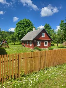 a small red house behind a wooden fence at Šimtametis namelis in Anykščiai