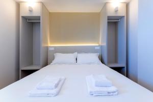 a bedroom with a large white bed with towels on it at Appart'hotel Saint Francois in Calvi
