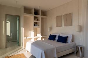 a bedroom with a white bed with blue pillows at CAPO LEFKADA Villa 71 - Sea View - Two Private Pools in Tsoukalades