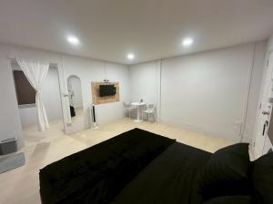 a white room with a bed and a tv at K-YA house in Phitsanulok
