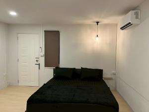 a bedroom with a black bed in a white room at K-YA house in Phitsanulok