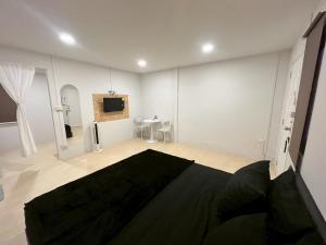 a white room with a bed and a tv in it at K-YA house in Phitsanulok