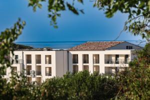 a white building with the ocean in the background at Appart'hotel Saint Francois in Calvi