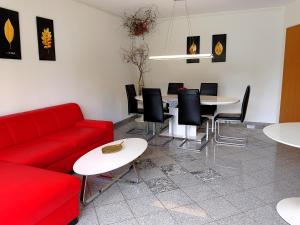 a living room with a red couch and tables and chairs at Ferienhaus Ringelwiese in Schönstedt