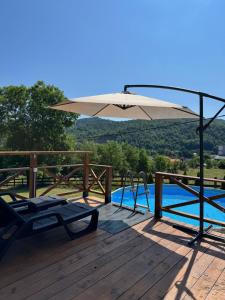 a patio with an umbrella next to a swimming pool at Brvnara Beli in Gornji Milanovac