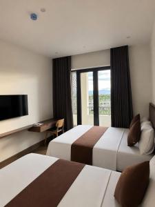 a hotel room with two beds and a flat screen tv at LunaB Hotel in Dong Hoi
