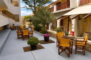 a patio with wooden chairs and tables and plants at Marialena hotel in Archangelos