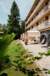 a resort building with a yard with chairs and a tree at Hotel Pod Jedlami in Wisła