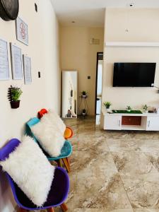 a living room with two chairs and a flat screen tv at Hola Properties in Dhaka
