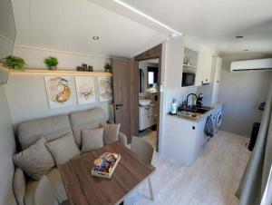 a living room with a couch and a table and a kitchen at Tiny house climatisé et jacuzzi privatif in Saint-Loup-Nantouard