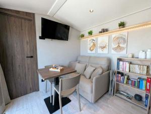 a living room with a couch and a table at Tiny house climatisé et jacuzzi privatif in Saint-Loup-Nantouard