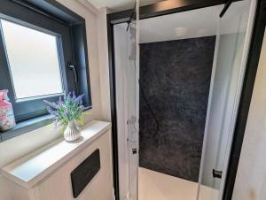 a bathroom with a shower with a glass door at Tiny house climatisé et jacuzzi privatif in Saint-Loup-Nantouard +35 photos